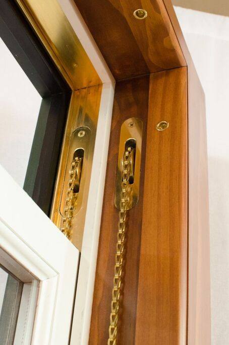 Close-up of restored brass sash hardware and chain on a wood window frame